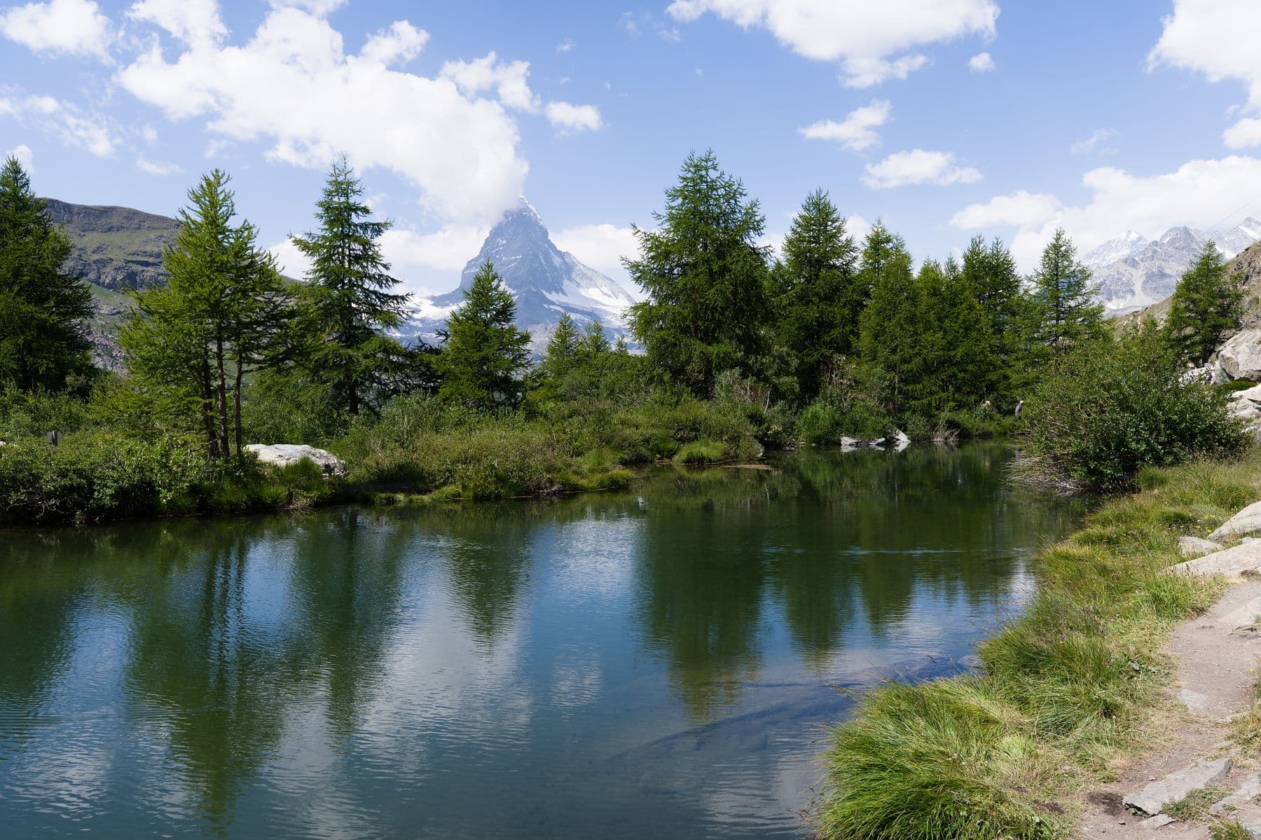 The Matterhorn reflected in an alpine lake near Zermatt, framed by larches